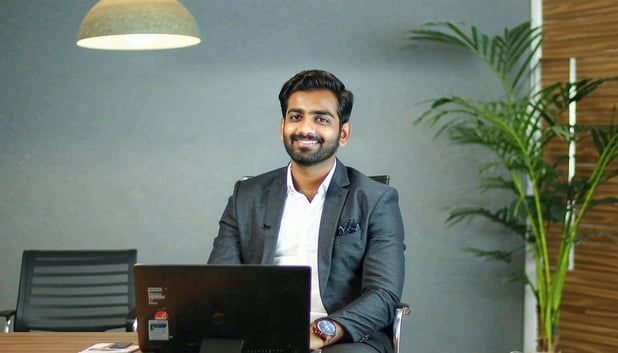 create an image where a confident Indian professional man is appearing for an interview in front of the interviewer The interview room is aesthetic